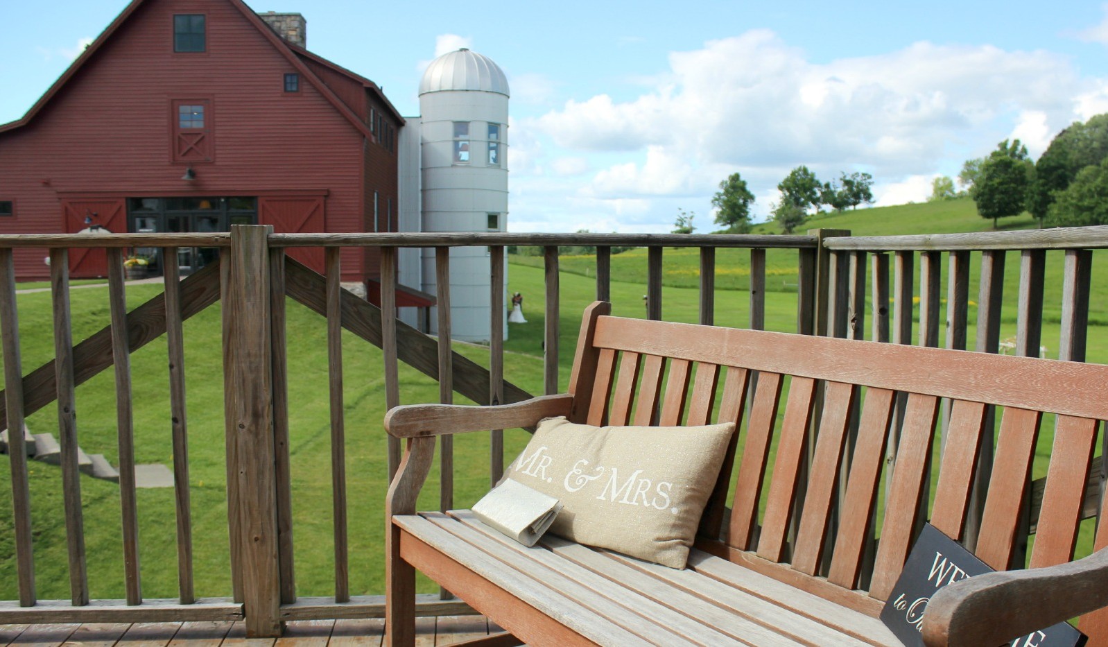 Pillow with the words Mr & Mrs on bench with barn in background 