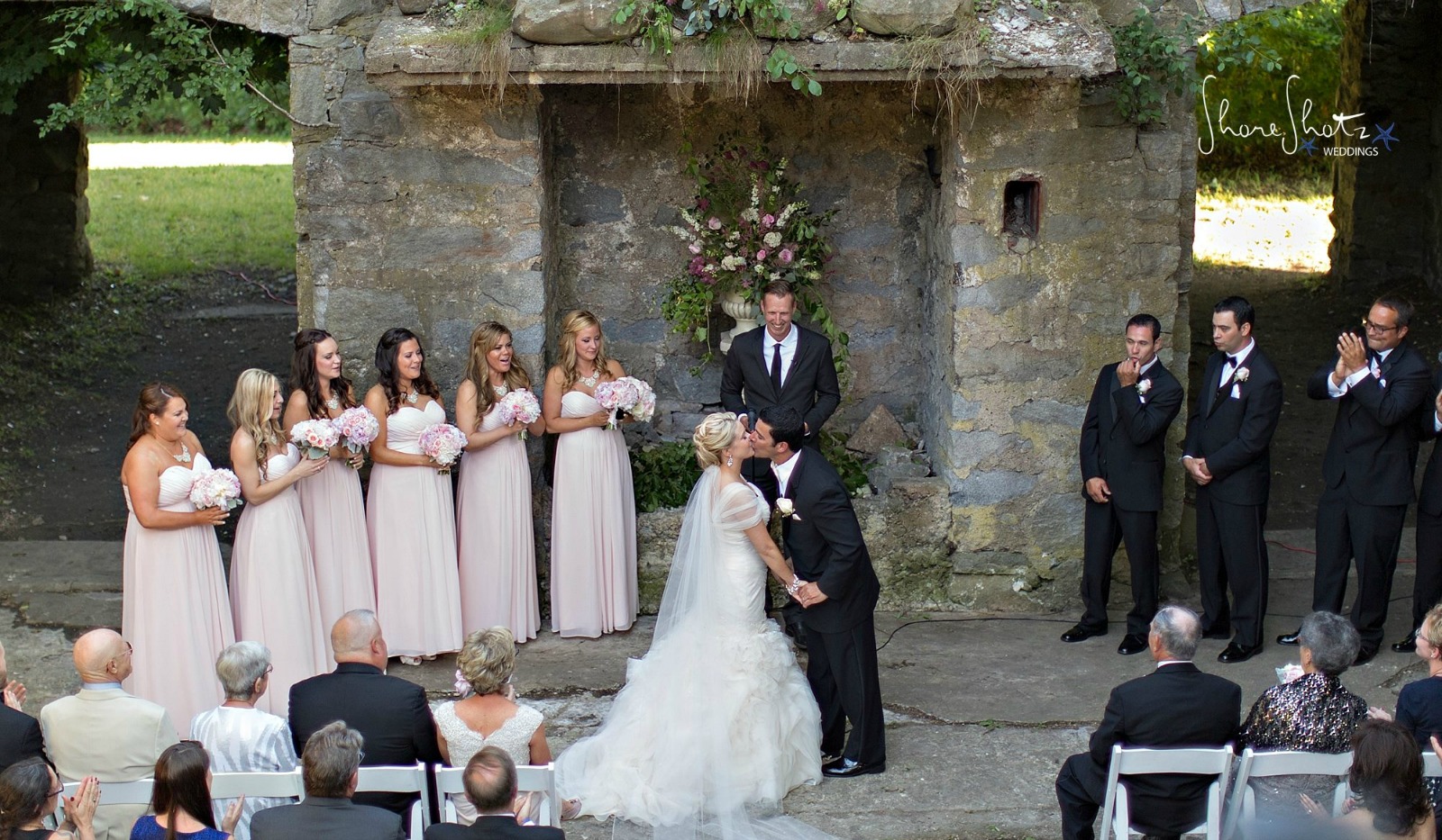 Bride and groom kissing at stone home ruins after wedding ceremony